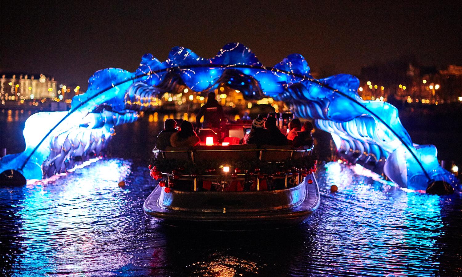 People in a boat, cruising underneath the colourful artwork