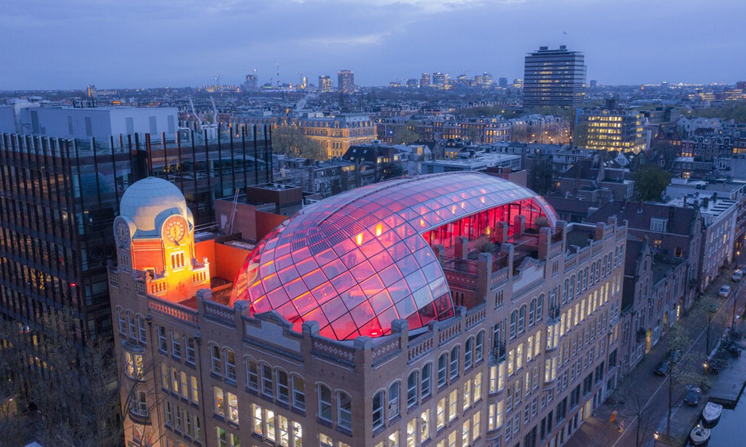 Aerial view of the office building, with the high light event space on the roof lit.